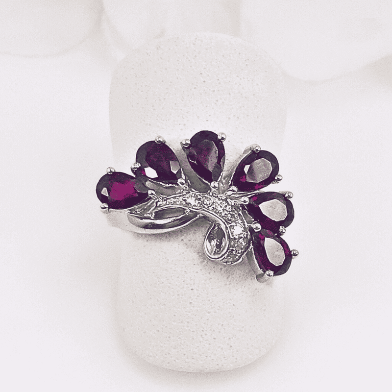 Close-up view of the Crimson Horizon Ring, featuring six rhodolite garnet gemstones arranged in a horizontal swirl pattern, set in an intricately detailed silver band