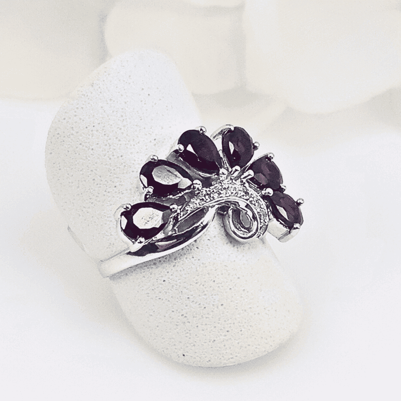 featuring six rhodolite garnet gemstones arranged in a horizontal swirl pattern