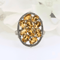 Close-up view of the Lemon Radiance Ring, featuring a large oval design with small iridescent oval citrine gemstones set in a sleek silver band with intricate details.